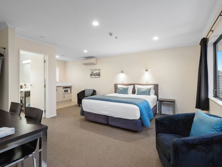 A hotel room with a bed, a desk, a chair, and a window.