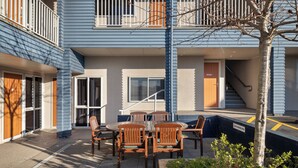 A building with a balcony, a staircase, and a pool area. - ASURE Aveda Motor Lodge (Pukekohe)
