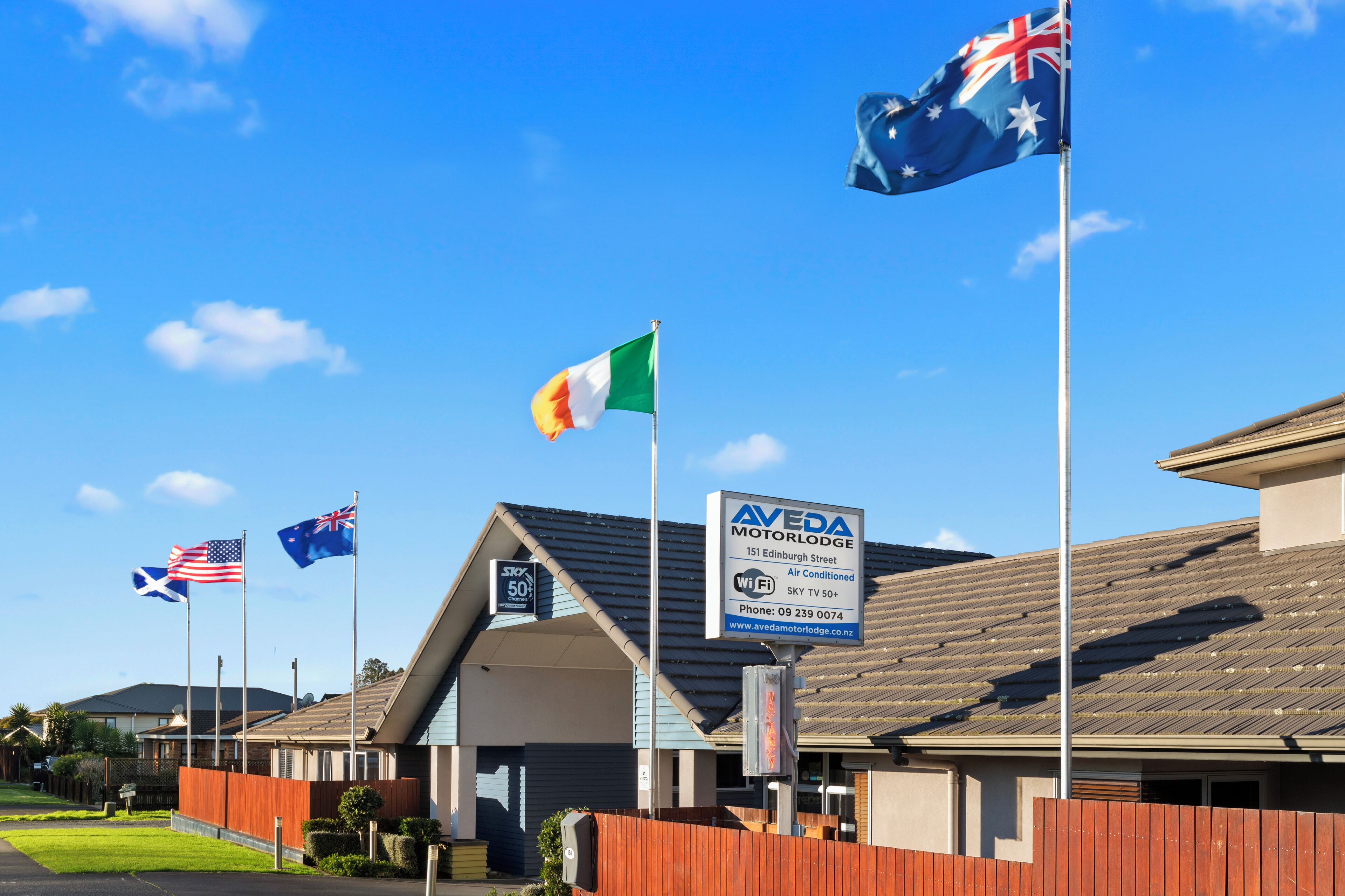 Un edifici amb diverses banderes, entre elles l'australiana i la nord-americana, i un cartell de Aveda Motor Lodge.
