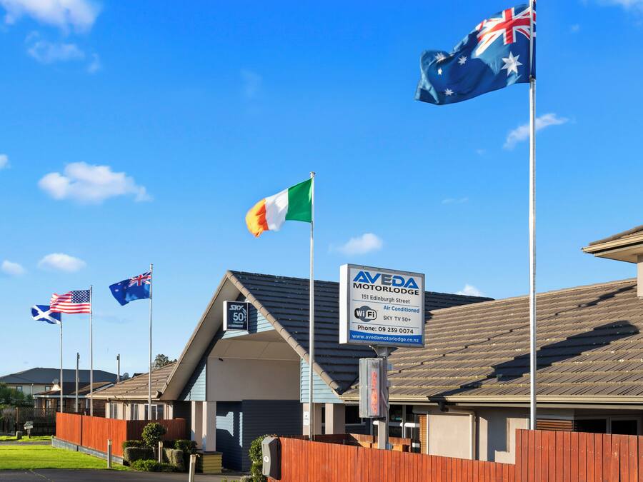 A building with multiple flags, including the Australian and American flags, and a sign for Aveda Motor Lodge.