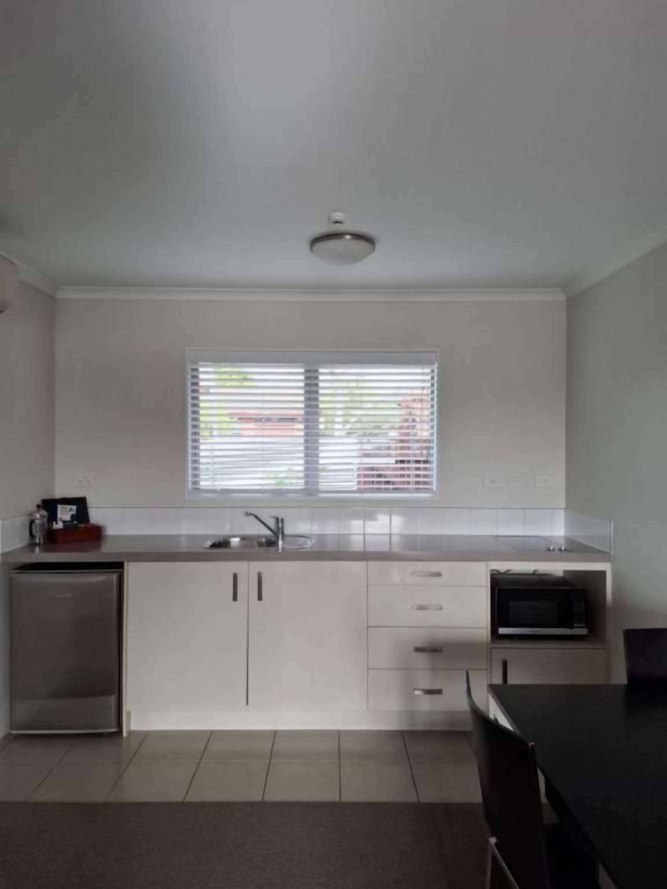 A modern kitchen with white cabinets, a microwave, and a sink.