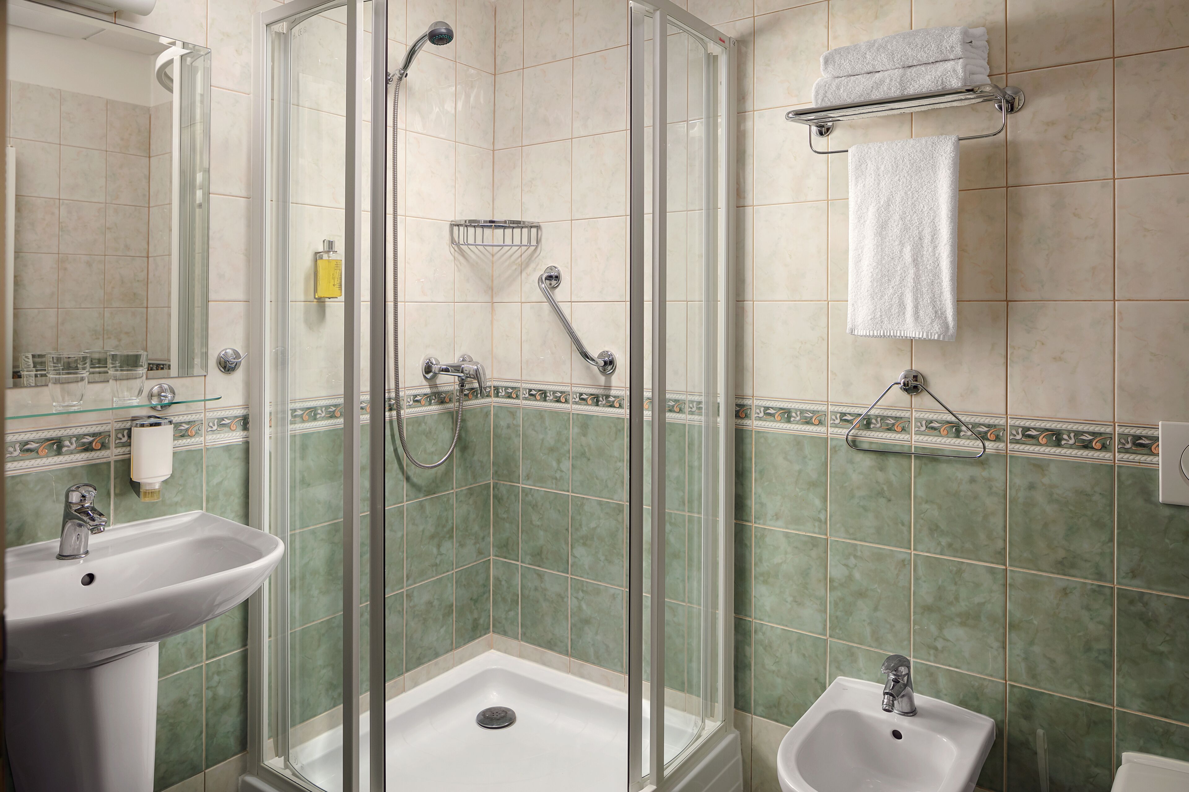 A bathroom with a glass-enclosed shower, a sink, and a bidet.