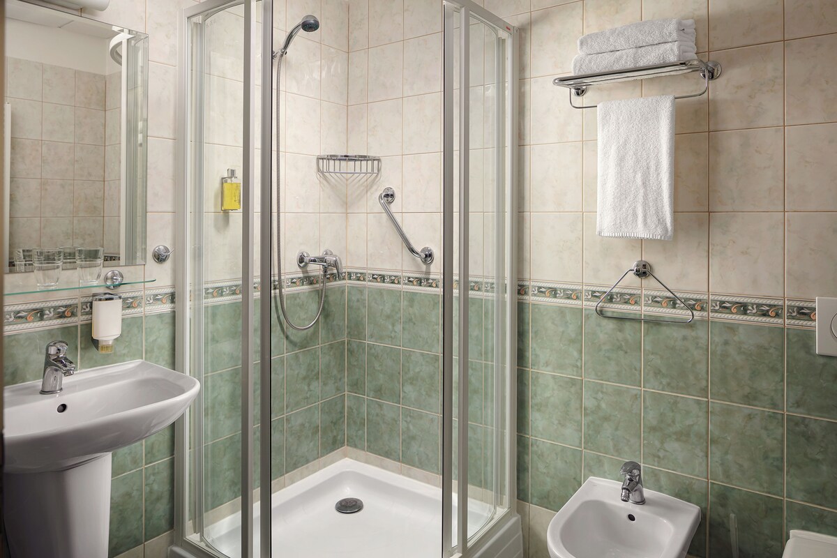A bathroom with a glass-enclosed shower, a sink, and a bidet.