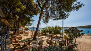 An outdoor seating area with wicker furniture and a view of the sea. -  Hotel Medena Budget (Seget)