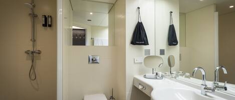 A modern bathroom with a shower, toilet, and a large sink with a mirror.