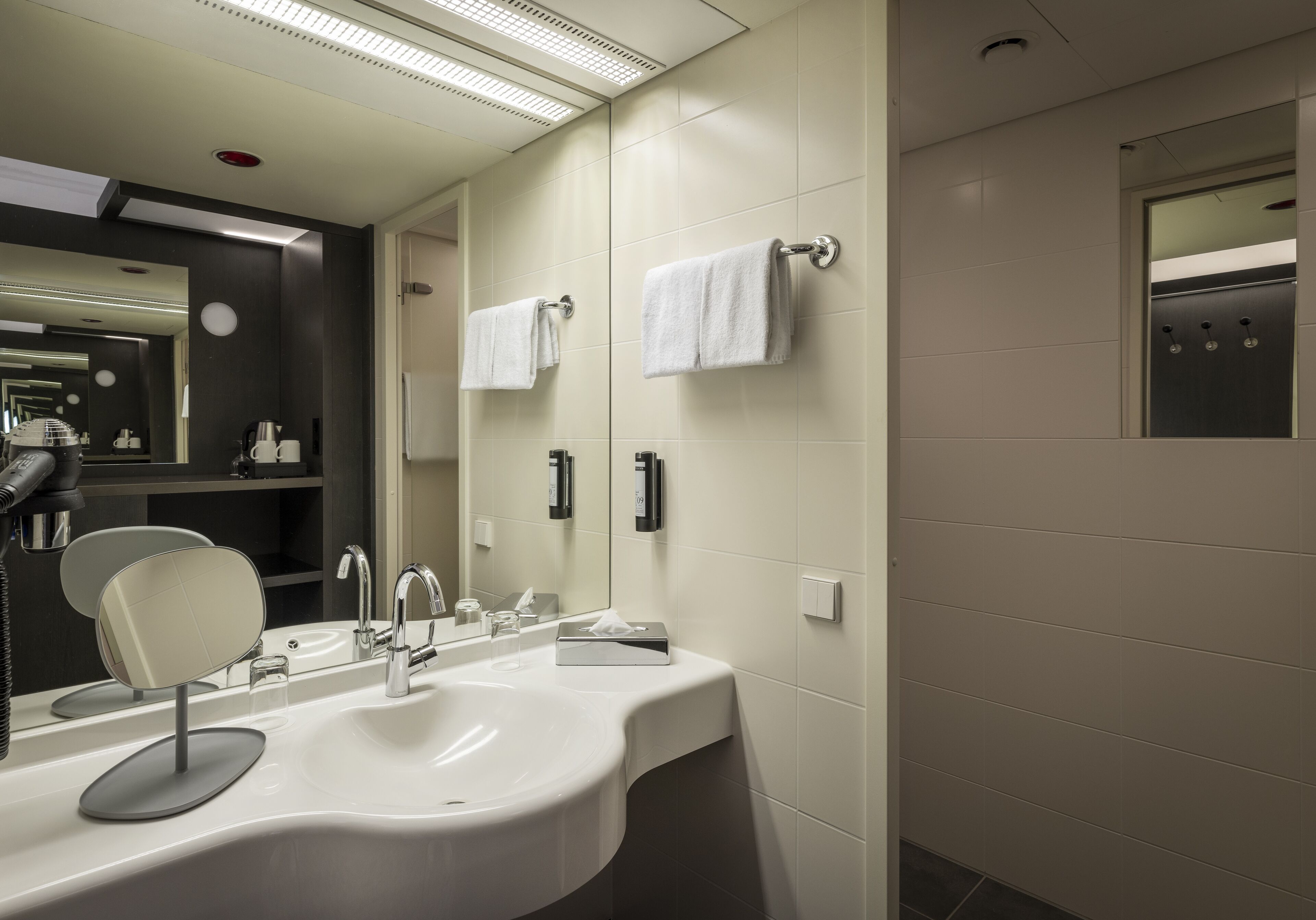 Ein modernes Badezimmer mit einem großen Spiegel, zwei Waschbecken und einem Handtuchhalter.