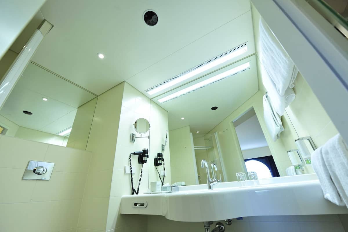 Un baño moderno con un espejo grande, un lavabo y un secador de pelo montado en la pared.