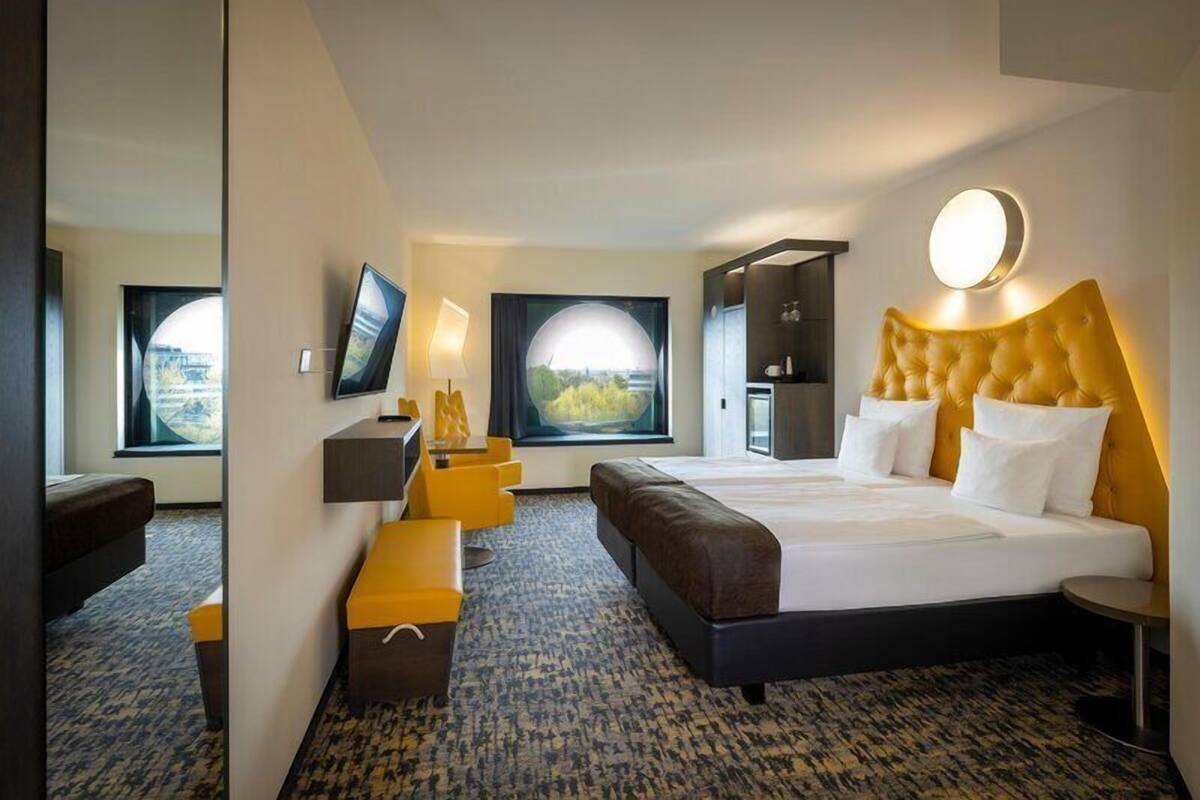 Habitación de hotel con una cama grande, un escritorio, una silla, un televisor y una ventana con vistas.