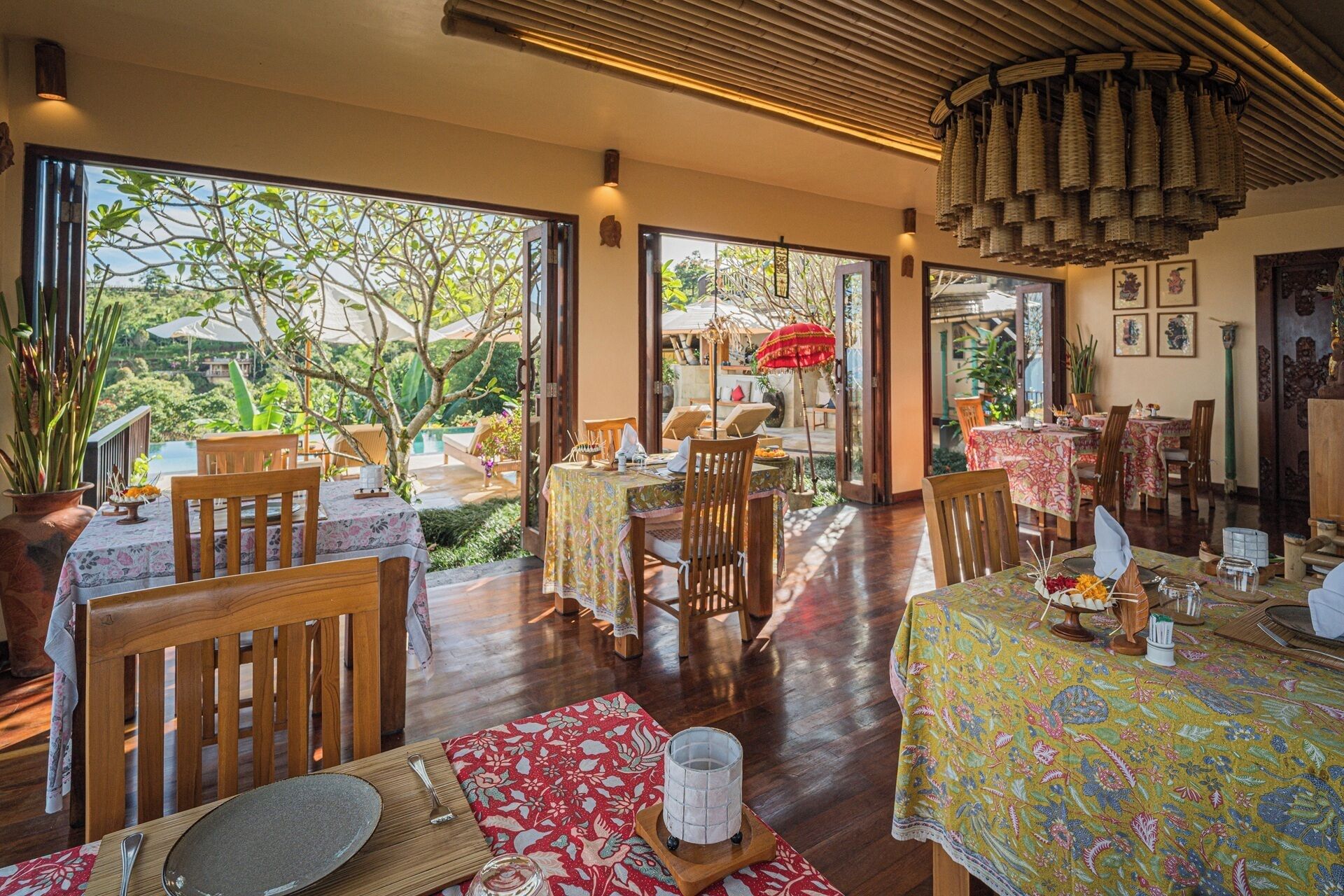 A restaurant with outdoor seating, wooden furniture, and a view of greenery.
