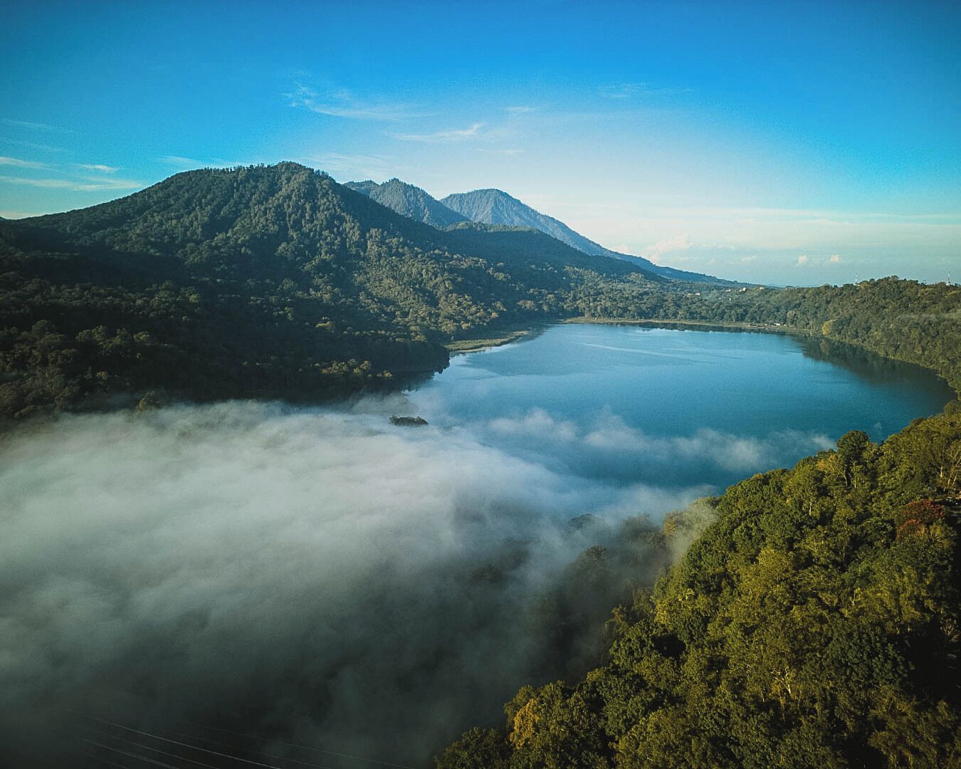 A mountainous landscape with a lake surrounded by dense forest.