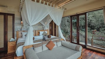 A bedroom with a canopy bed, wooden headboard, and a view of the garden.