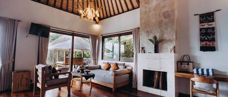 A spacious living room with a wooden floor, a sofa, a chair, and a fireplace.