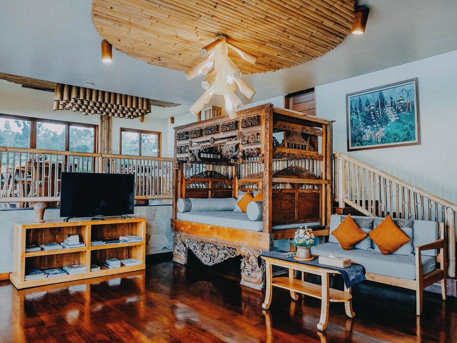 Un salón amplio con una escalera de madera, un televisor y una estantería.