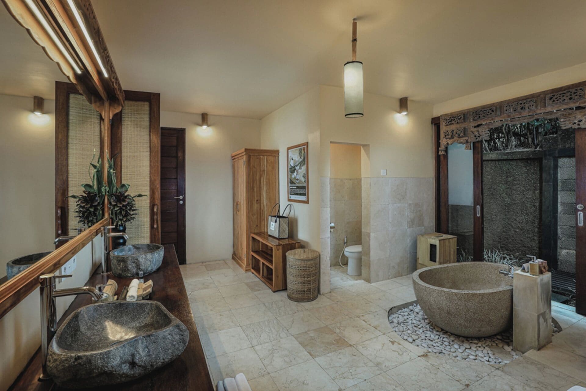 A bathroom with a stone sink, a large stone bathtub, a wooden cabinet, and a mirror with a wooden frame.