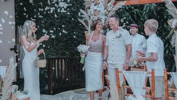 Una ceremonia de boda con invitados sentados en mesas, decoradas con flores blancas y pastos del pampa.