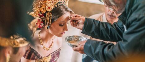 A person in traditional attire receiving a ritualistic offering.
