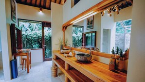 A wooden dining area with a bench, a table, and a large mirror reflecting the room.