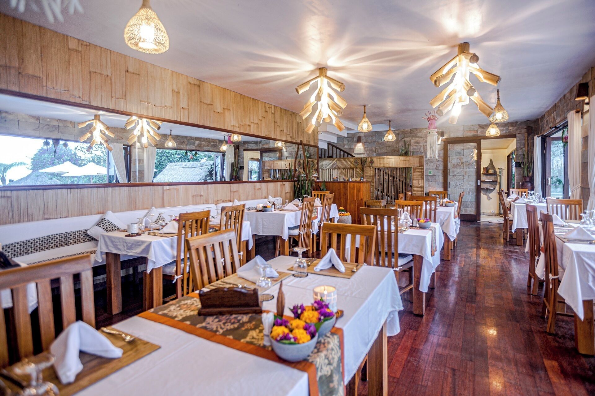 A restaurant with wooden walls, multiple tables, and hanging light fixtures.