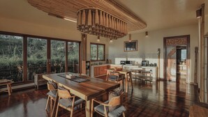A spacious kitchen with a large dining table and chairs, a hanging light fixture, and a view of the outdoors.
