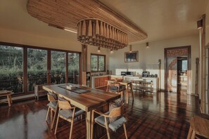 A spacious kitchen with a large dining table and chairs, a hanging light fixture, and a view of the outdoors.