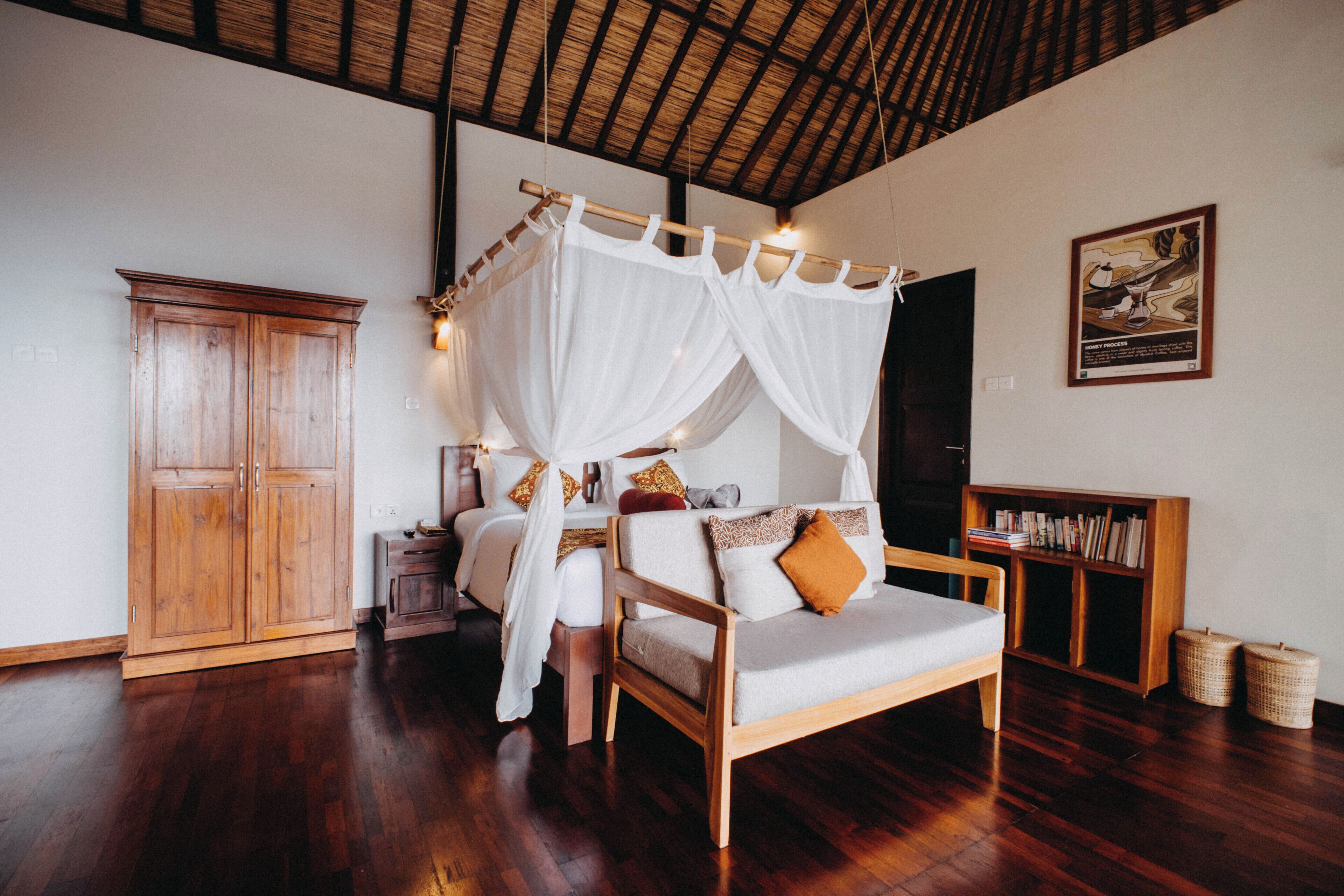 A bedroom with a canopy bed, wooden wardrobe, and a bookshelf.