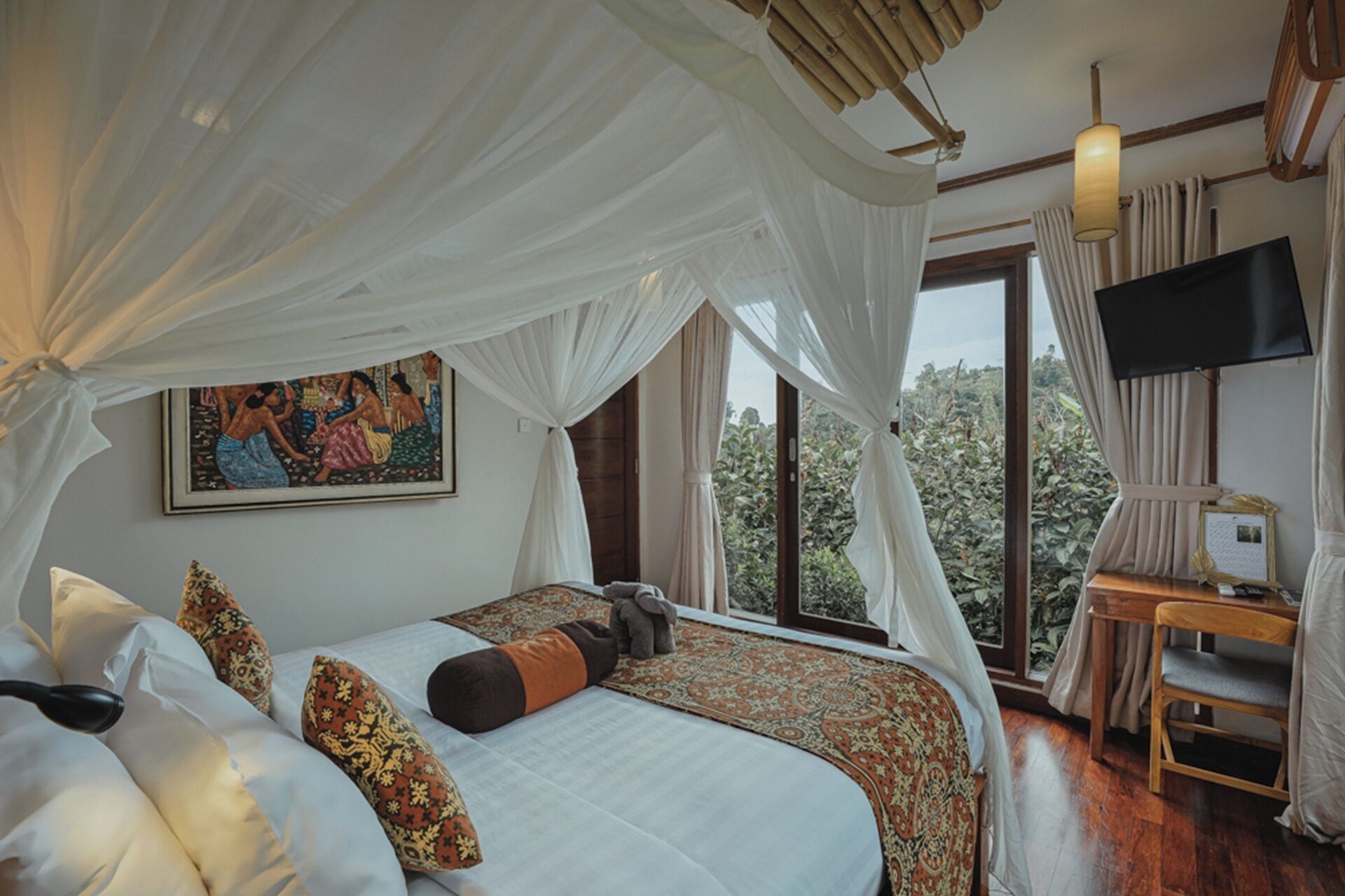 A bedroom with a bed, a television, and a window with a view of greenery.