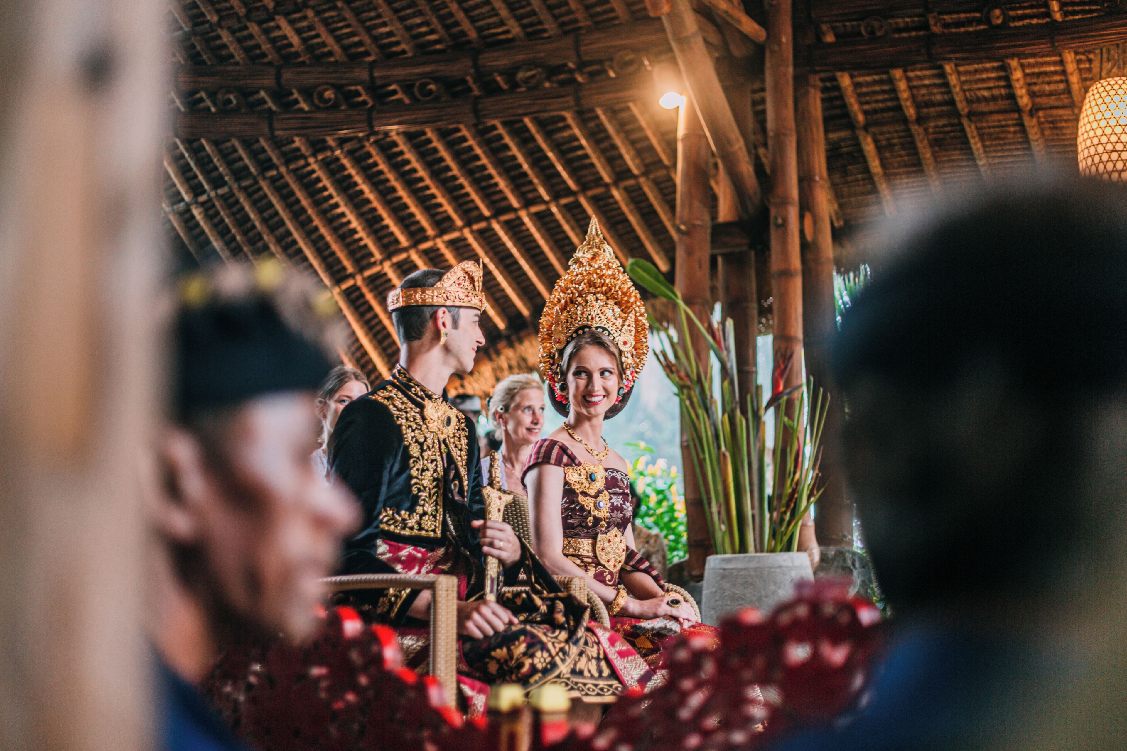 A traditional ceremony with ornate costumes and a thatched roof structure.