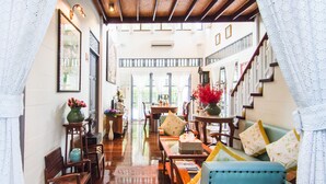 A spacious living area with wooden furniture, a blue sofa, and a staircase leading to an upper level. - Baan Noppawong (Bangkok)