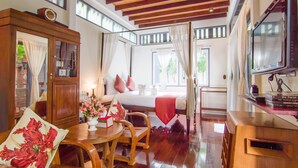 A room with a bed, a TV, a wooden cabinet, and a table with chairs. - Baan Noppawong (Bangkok)