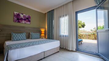 A hotel room with a bed, a nightstand, a lamp, a window with curtains, and a view of the outside.