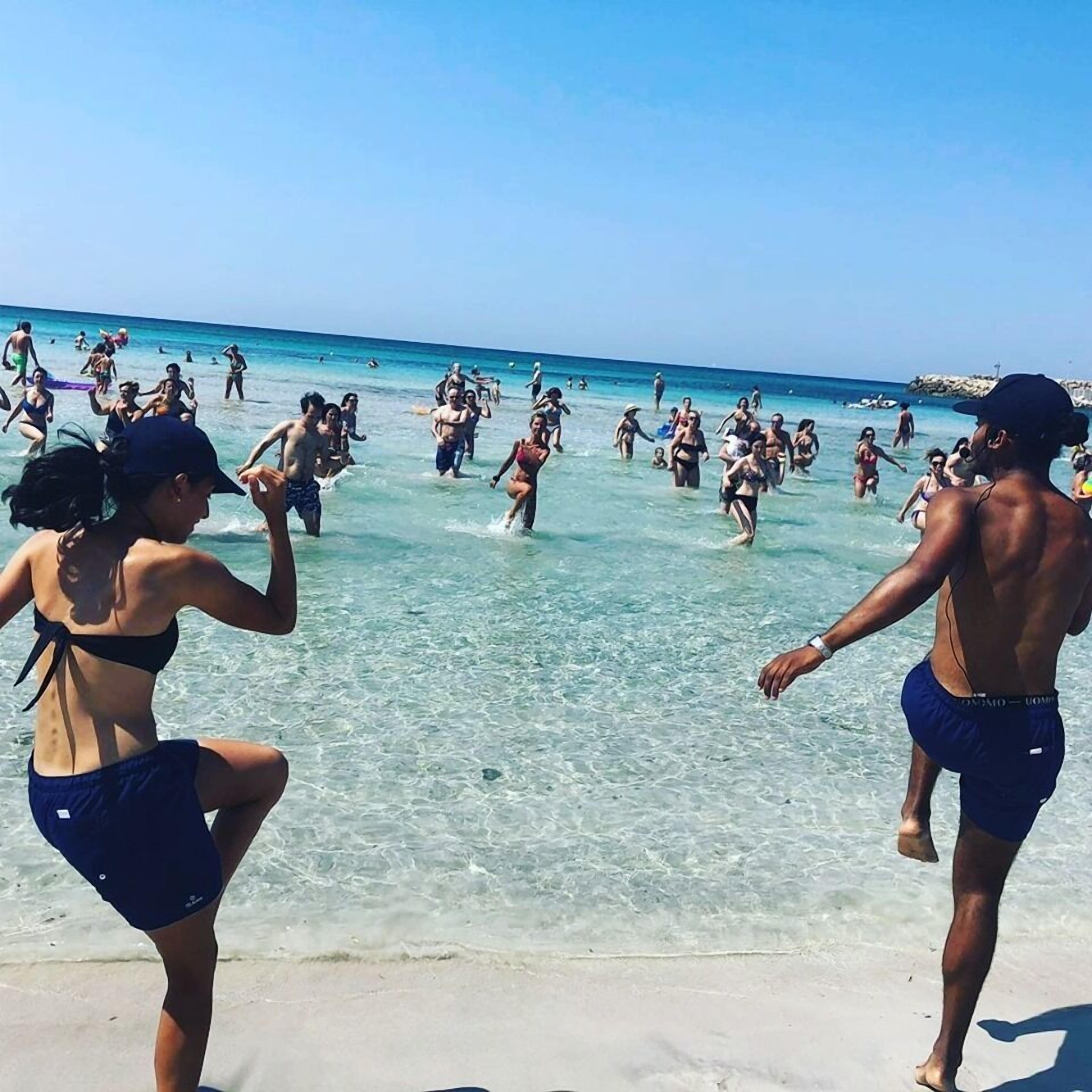 Una spiaggia con persone che nuotano e camminano nell'acqua.