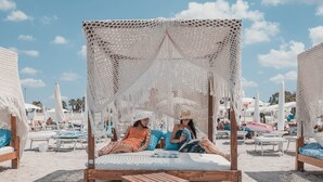 Una cabaña en la playa con una hamaca y muebles de madera.