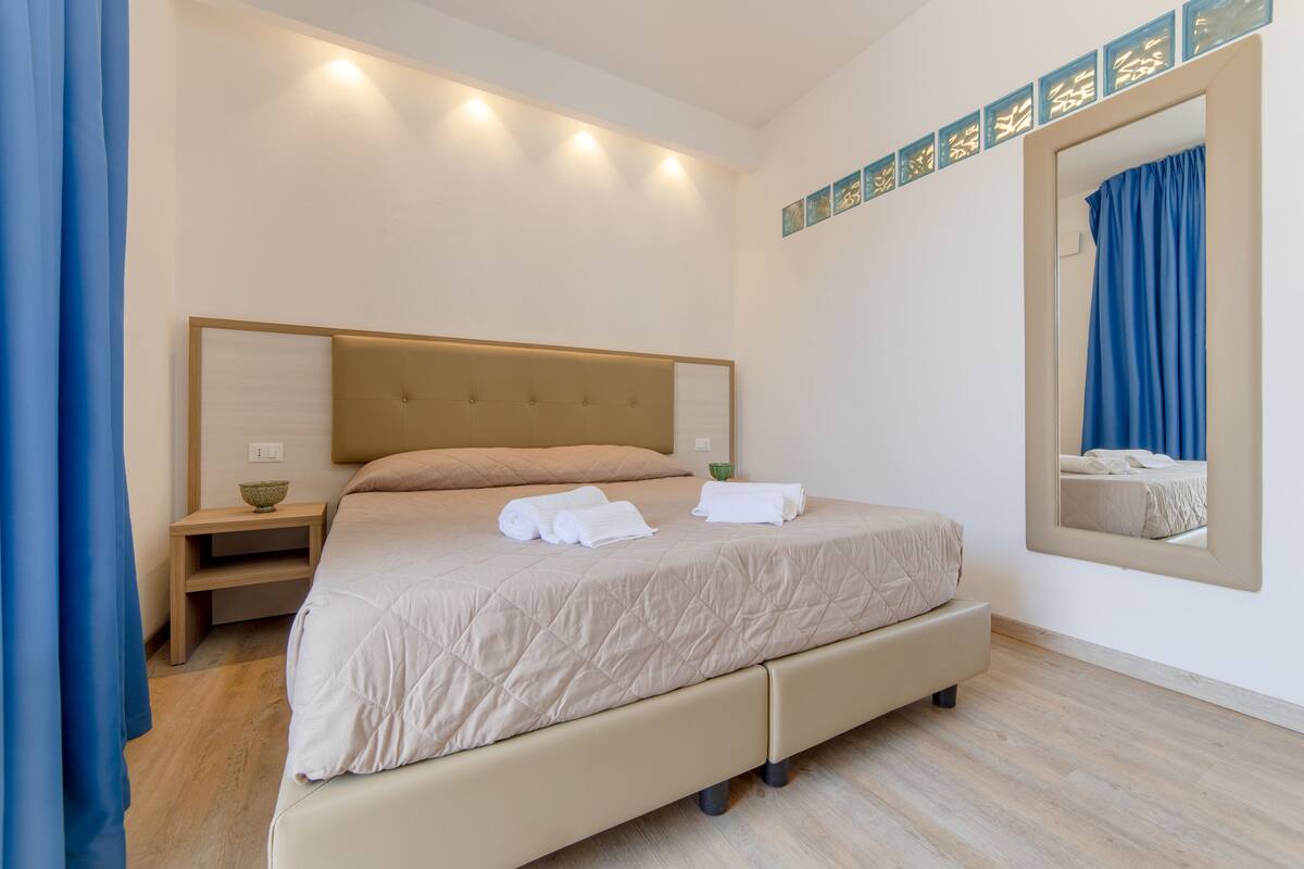 Une chambre d’hôtel moderne avec un grand lit, des tables de chevet et un miroir.