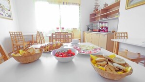 A breakfast setting with bread, tomatoes, cheese, and ham on a table. - Casa Del Sole Relax Room (Castrignano del Capo)