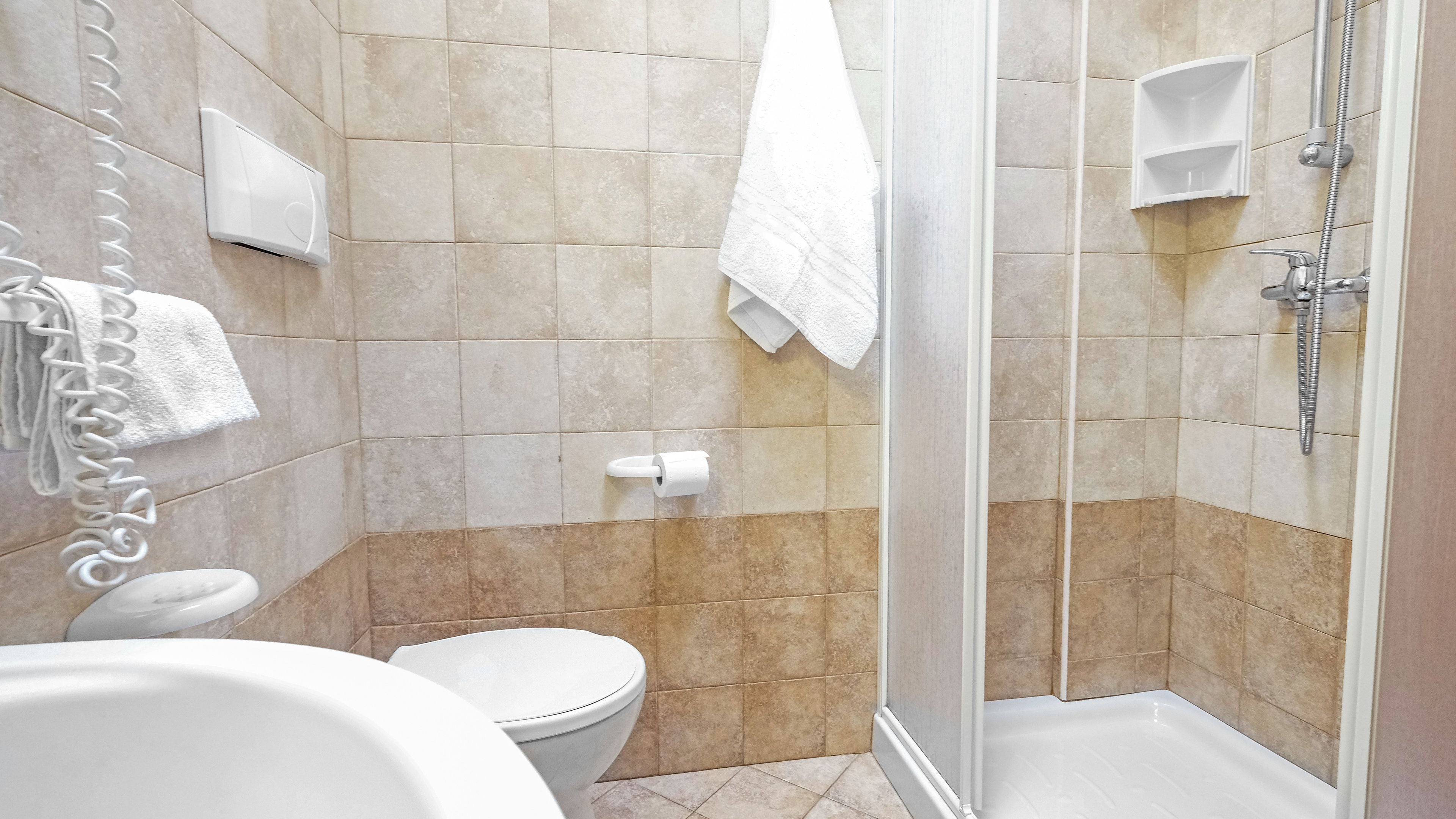 A bathroom with a toilet, a shower, and a sink.