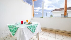 Un balcón con una mesa dispuesta para el desayuno, que incluye un croissant, una taza y un vaso de zumo de naranja.