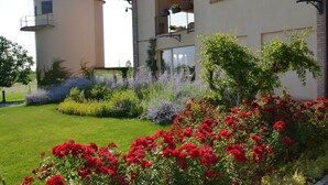Un edificio con una torre cilíndrica, un balcón con macetas y un jardín bien cuidado con diversas flores.