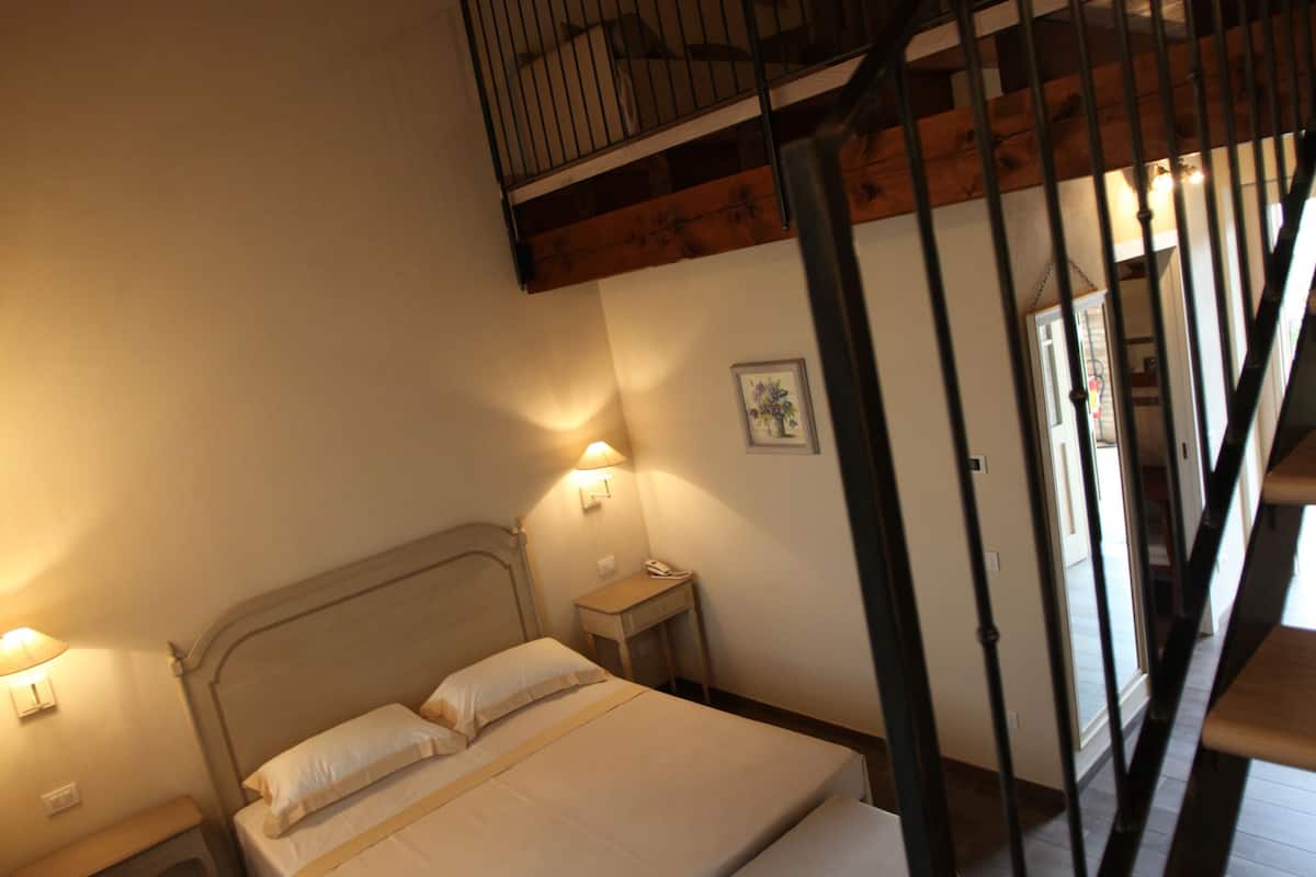 A bedroom with a bed, bedside tables, and a staircase.
