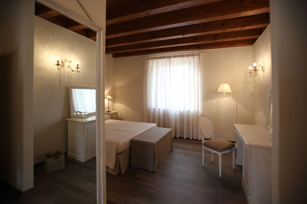 A bedroom with a bed, bedside tables, a chair, and a desk with a mirror.
