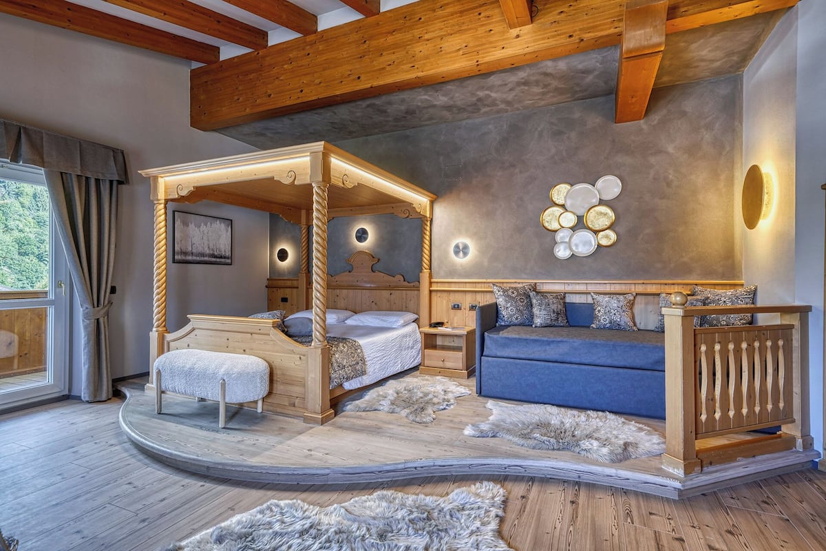 Ein Schlafzimmer mit Himmelbett, einer Couch und einer Holzbank.