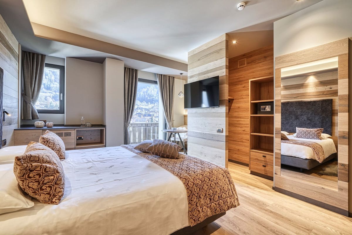 Ein modernes Schlafzimmer mit einem großen Bett, einem an einer Holz Wand montierten Fernseher und einem eingebauten Kleiderschrank.