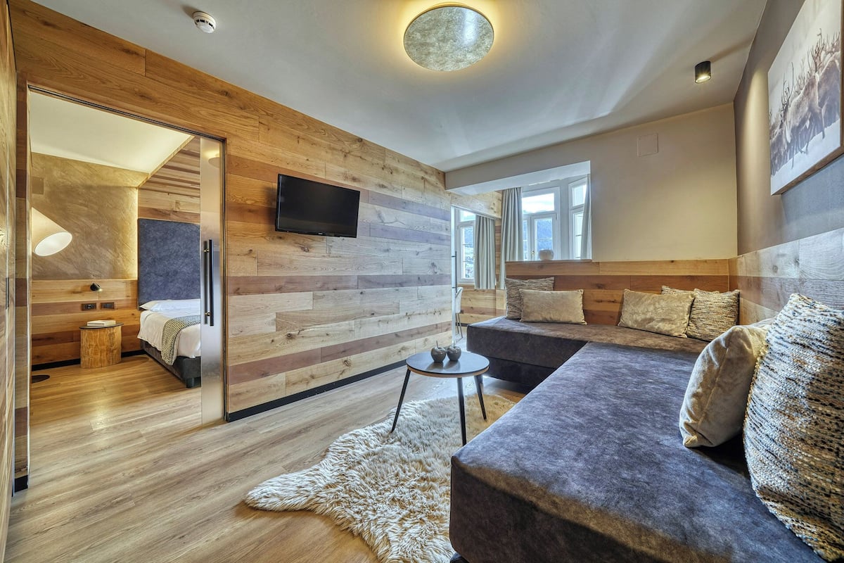 Ein modernes Interieur mit einer Holzwand, einem Sofa, einem Fernseher und einem Fenster.