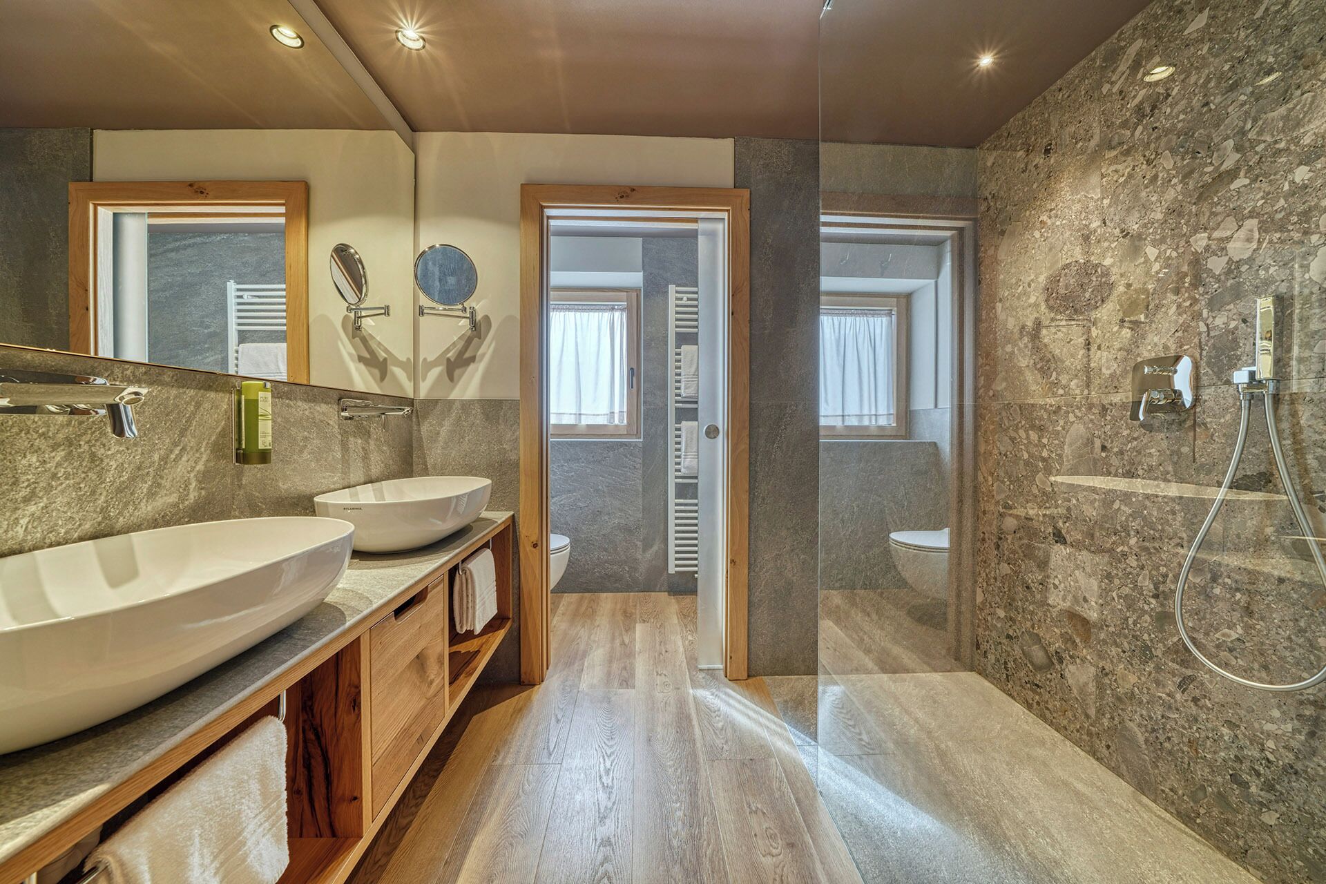 A modern bathroom with two sinks, a mirror, and a shower.