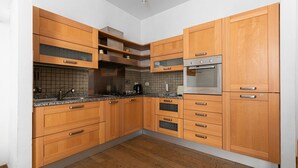Une cuisine avec des meubles de rangement en bois, un four encastré et un four à micro-ondes.