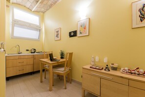 Une cuisine de taille réduite avec une table en bois, un ordinateur portable et une petite plante en pot.