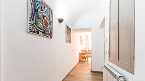 Un couloir doté d’un plancher en bois, de murs blancs et d’œuvres d’art.