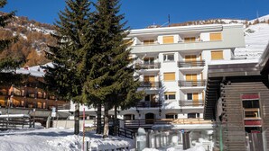 A multi-story building with balconies and a ski slope in the background. - Hotel Hermitage (Sestriere)