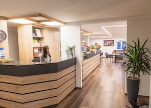 Una zona de recepción con mostrador de madera, un reloj y un panel informativo.