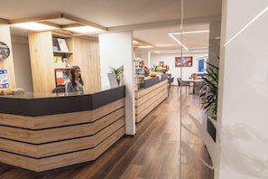 Una zona de recepción con un mostrador de madera, un reloj en la pared y un mostrador con diversos objetos.