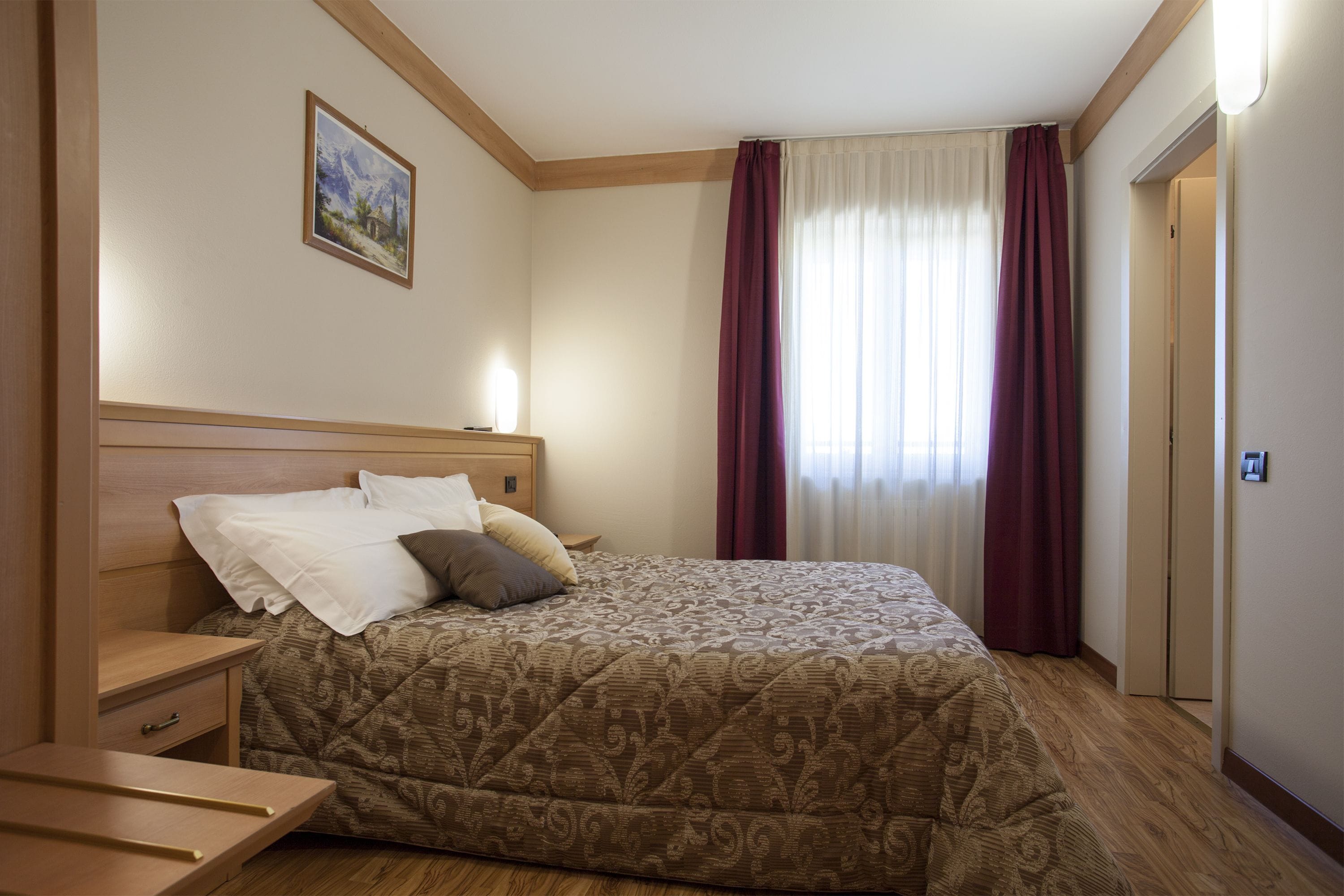 Una habitación de hotel con cama, mesita de noche y otra mesita auxiliar.